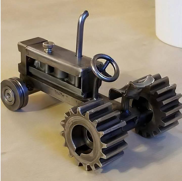 Metal vehicle sculpture with prominent gear-shaped wheels.