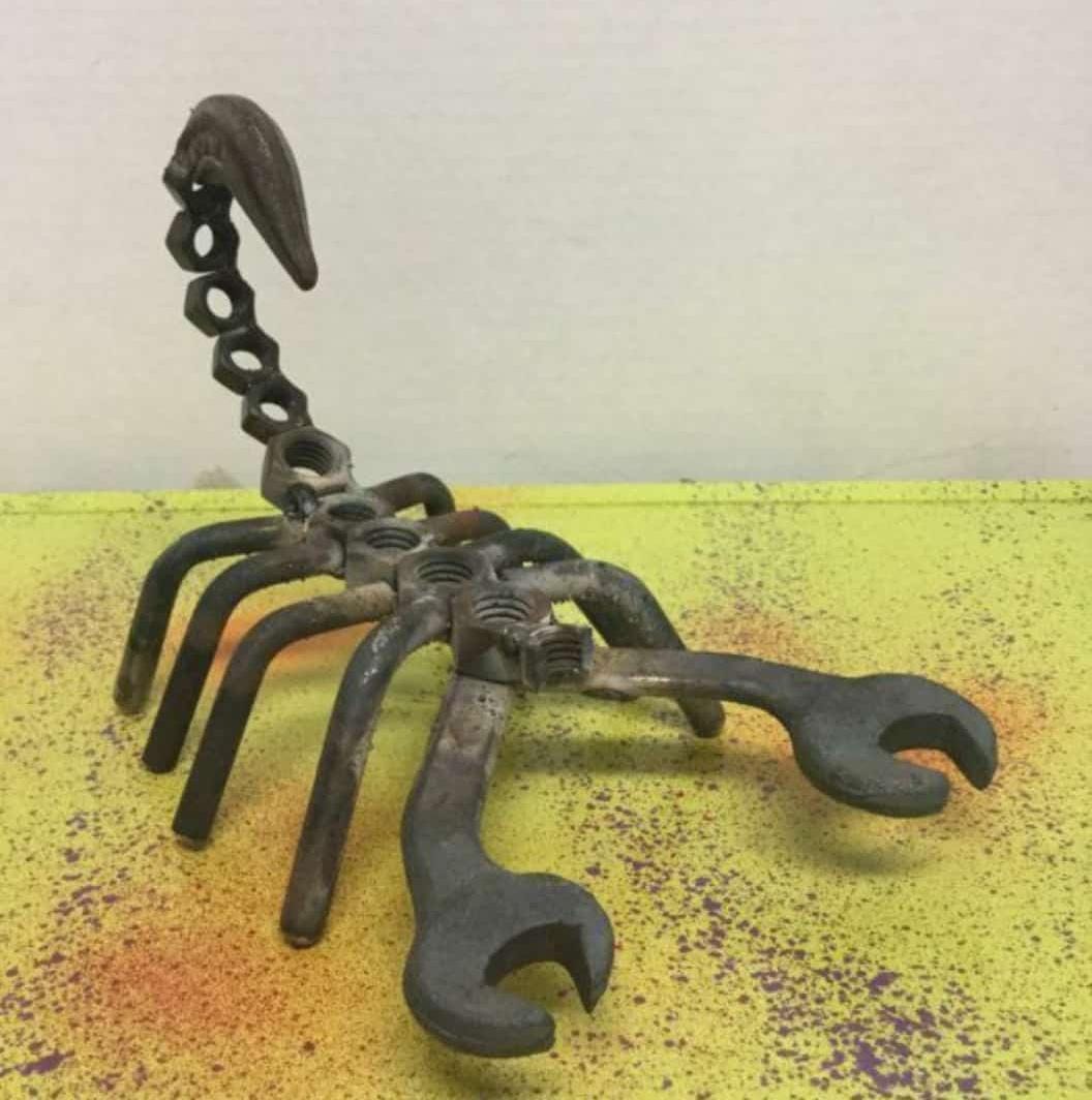 Sculptural metal creature assembled from wrenches and mechanical parts.