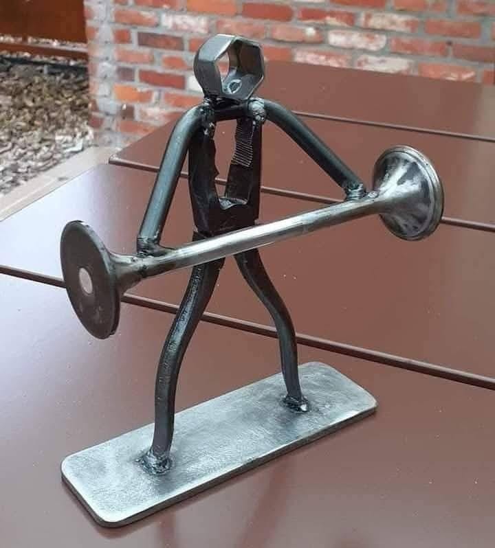 Metal human figure holding a horizontal bar on a small base.