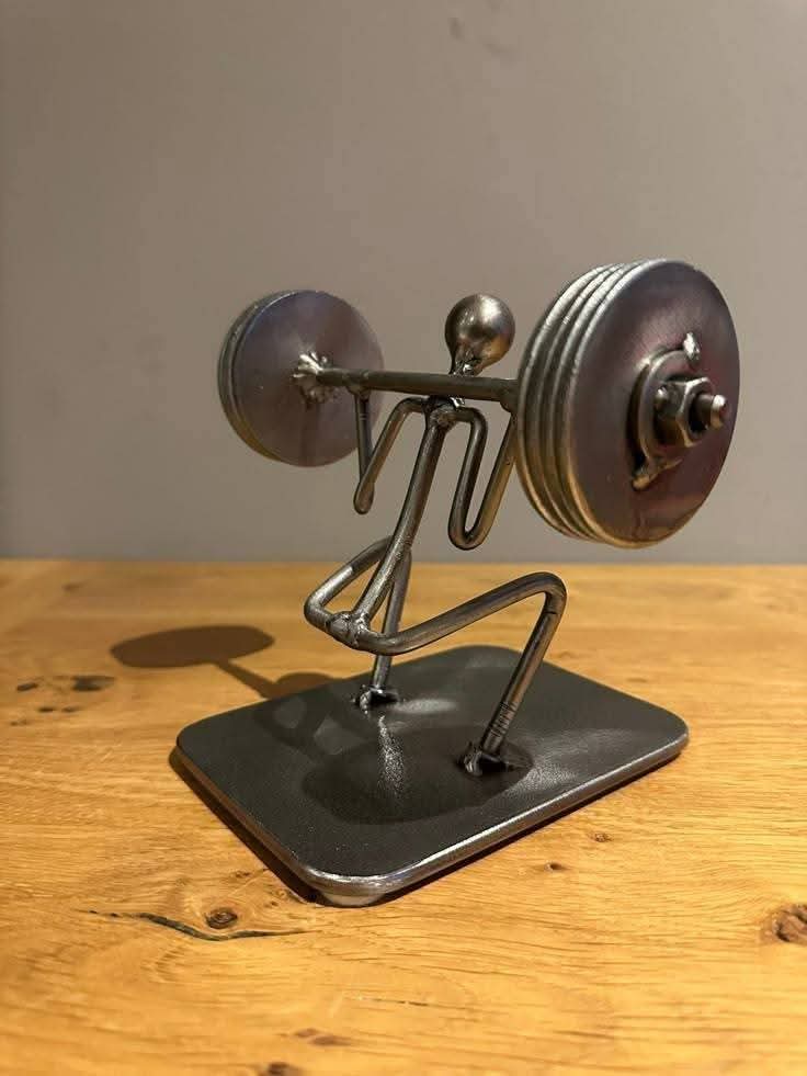 Metal figure lifting a barbell on a rectangular base.