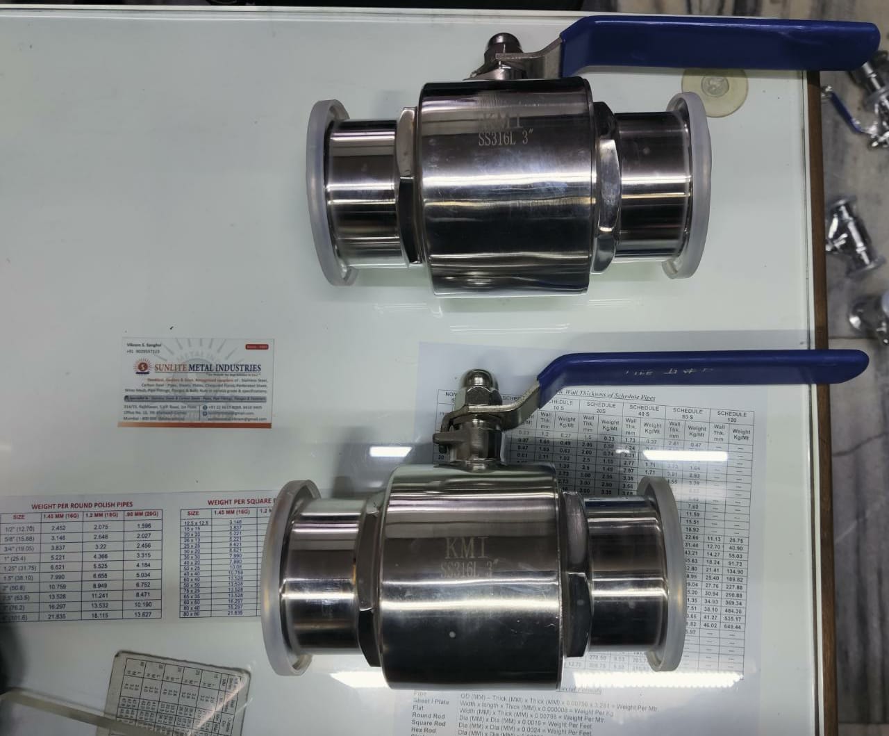 Two polished stainless steel sanitary ball valves with blue lever handles and tri-clamp end connections.