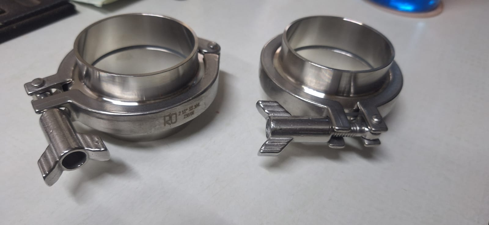 Two polished stainless steel sanitary TC clamps with hinged latch handles.