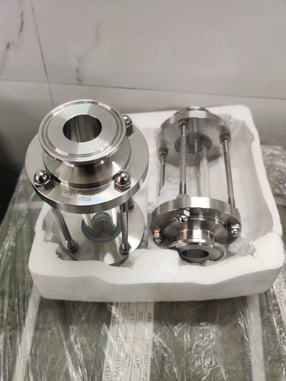 Two polished stainless steel view-glass assemblies with cylindrical sight sections, support rods and TC end connections.