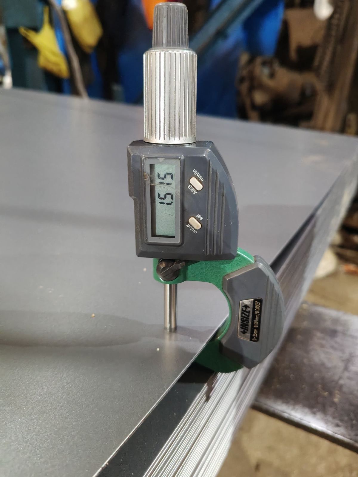 Calibrated digital micrometer measuring base metal thickness of a steel sheet to 0.01 mm precision